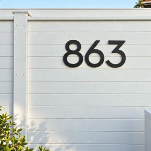 Matte black 30cm aluminium house numbers, 863, on a white fence at a coastal New Zealand home