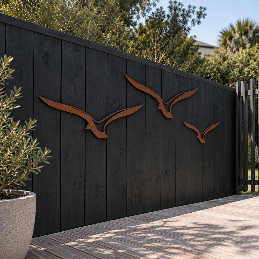 Set of three Corten steel albatross wall art pieces in flight, mounted outdoors on a fence in an Auckland garden