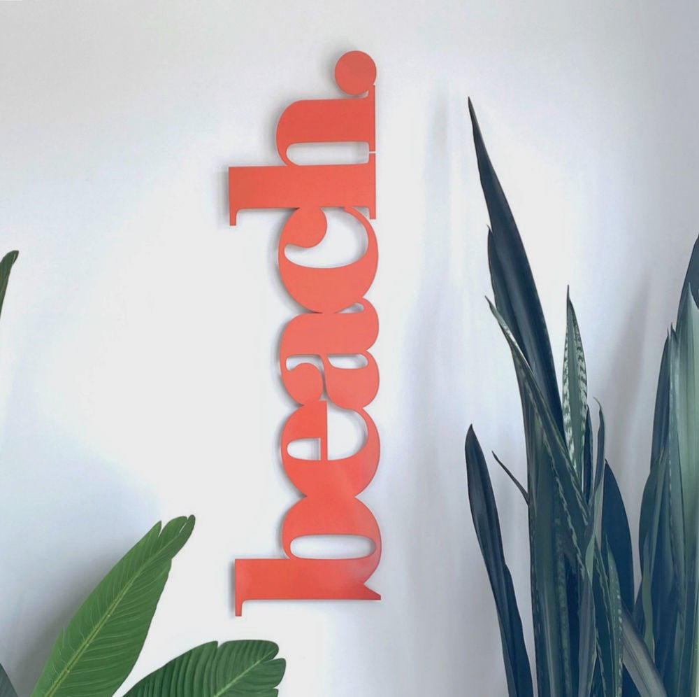 Orange beach decor on wall in modern coastal New Zealand home with tropical planting. 