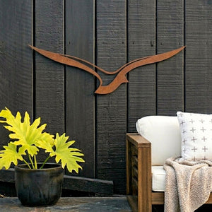 Corten steel outdoor metal art on black fence in New Zealand garden