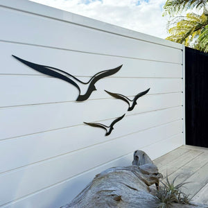 Close-up of black aluminium bird wall art on a backyard fence, weatherproof outdoor wall art designed in New Zealand.