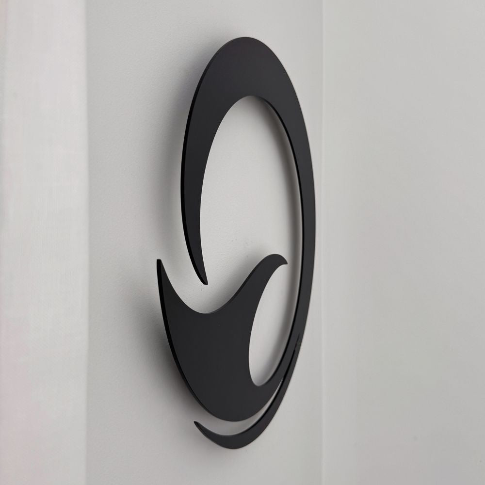 Matt black whale tail circle wall art next to a linen curtain in a New Zealand living room