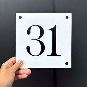 Hand holding a marine grade brushed stainless steel sign with black number '31' against a dark background in New Zealand. 