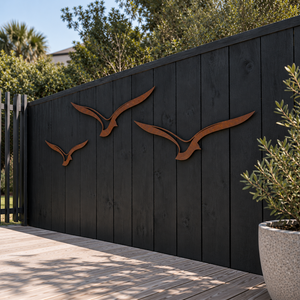 Set of three Corten steel albatross wall art pieces in flight, mounted outdoors on a fence in an Auckland garden