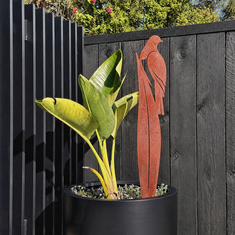 Rusted corten steel kereru on flax garden stake, 90cm tall, planted in a New Zealand garden border