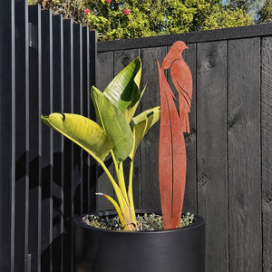 Corten steel kereru on flax garden stake in a planter in garden in Auckland. 