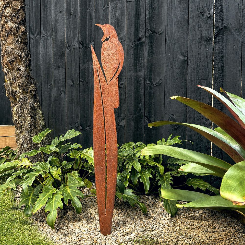 Rusted corten steel tui on flax garden stake, 90cm tall, standing in a New Zealand garden bed
