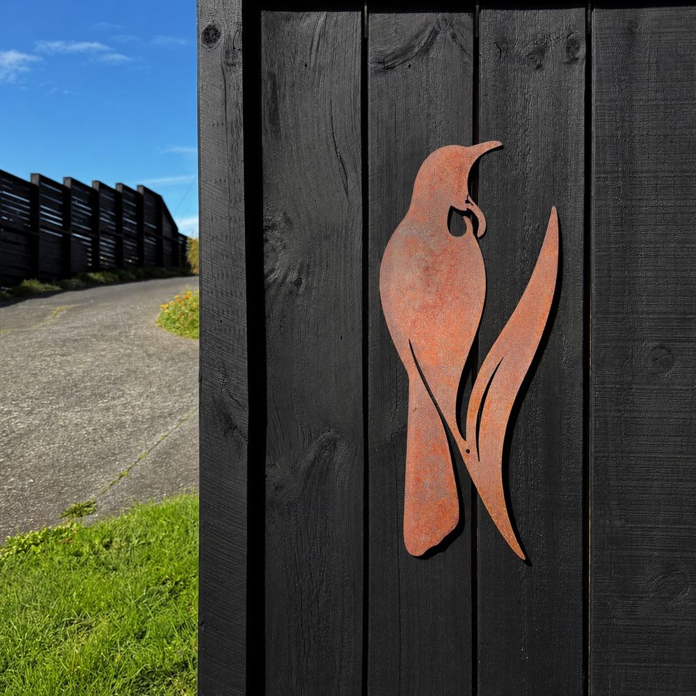 Corten steel tui silhouette wall art, 60cm tall, mounted on an outdoor wall in New Zealand