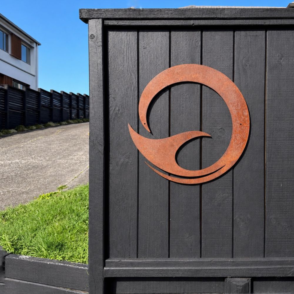 Corten steel whale tail wall art, 60cm circle, rusted and mounted on an outdoor wall in New Zealand