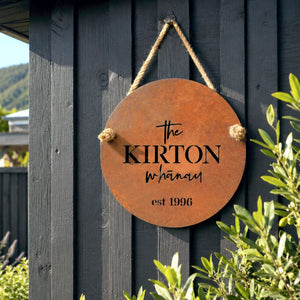 Custom corten steel family name sign mounted on a backyard fence at a modern New Zealand home