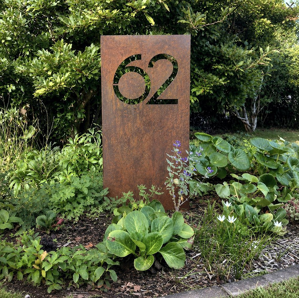 Large custom corten steel house number garden stake outside a rural New Zealand home, modern rusted steel address sign in landscaped front garden