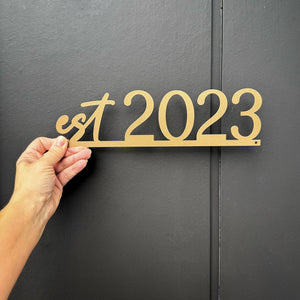 Matt gold stainless steel 'Est 2023' established house sign on a black New Zealand home