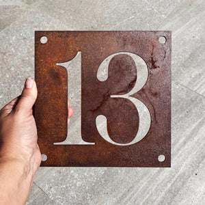 Small square corten steel house number sign with traditional font. 