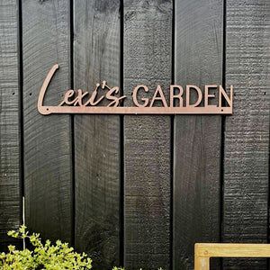 Corten steel custom sign on black fence in a New Zealand garden