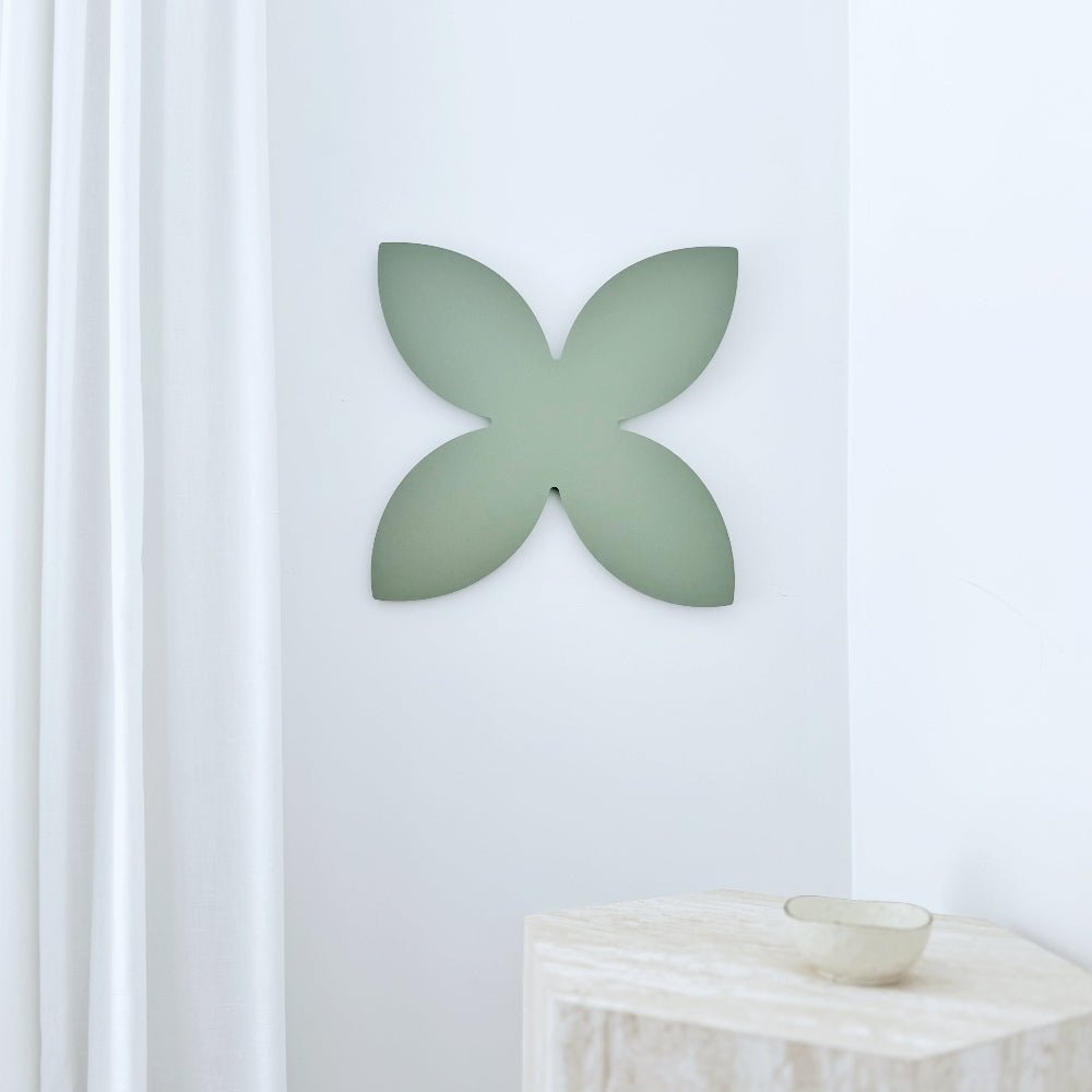 Decorative wall art with a green frangipani design on a white wall.