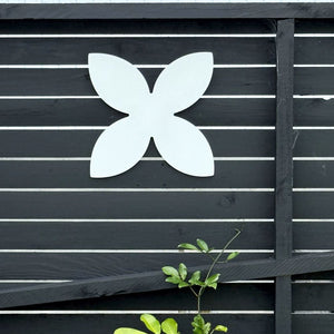 White frangipani steel wall art mounted on black fence in Lisa’s lush New Zealand garden