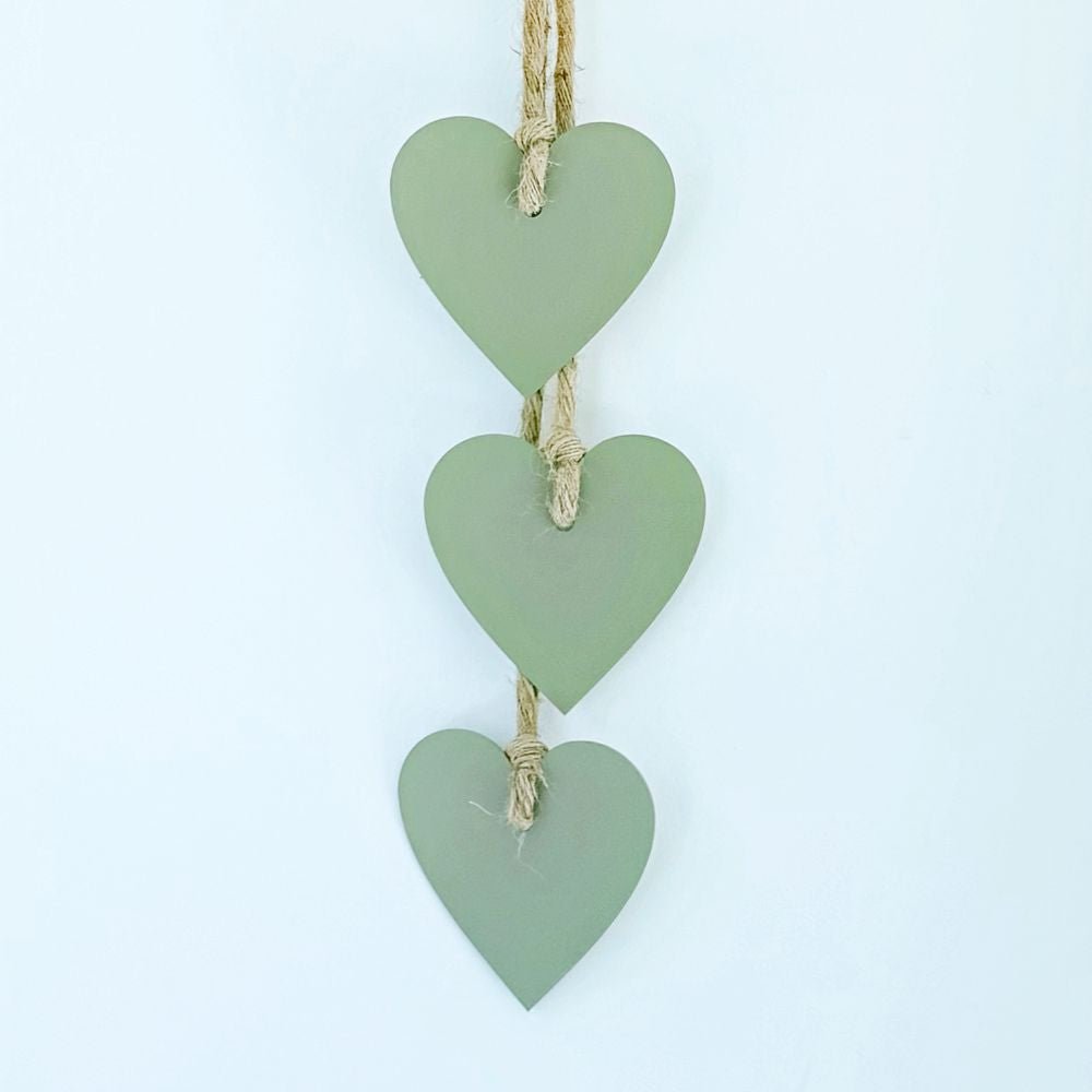 Decorative hanging with three green hears and a tassel on a white wall in a New Zealand home. 
