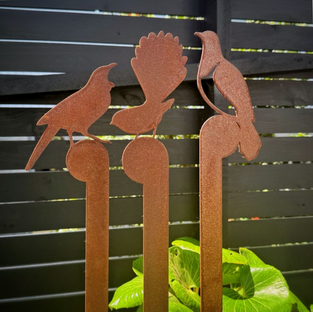 Close-up of tui, fantail and kererū corten steel bird sculptures in a New Zealand garden – NZ-made rusted steel garden art, native bird outdoor décor