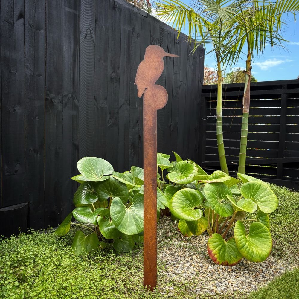 Large corten steel kingfisher garden sculpture stake in native New Zealand garden setting.



