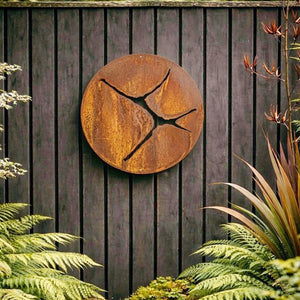 Kintsugi large round corten steel wall art on black wooden fence in NZ backyard