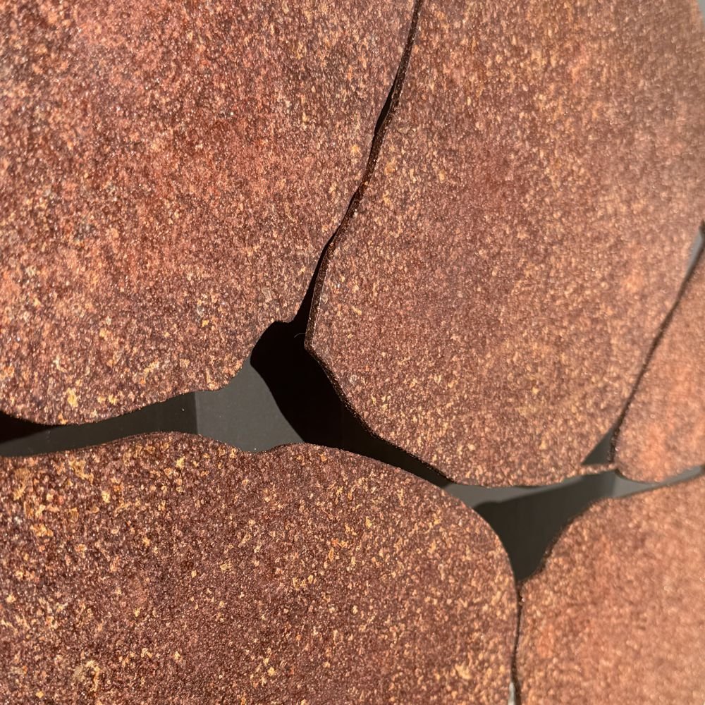 Corten steel large round outdoor wall art on black fence of modern NZ home