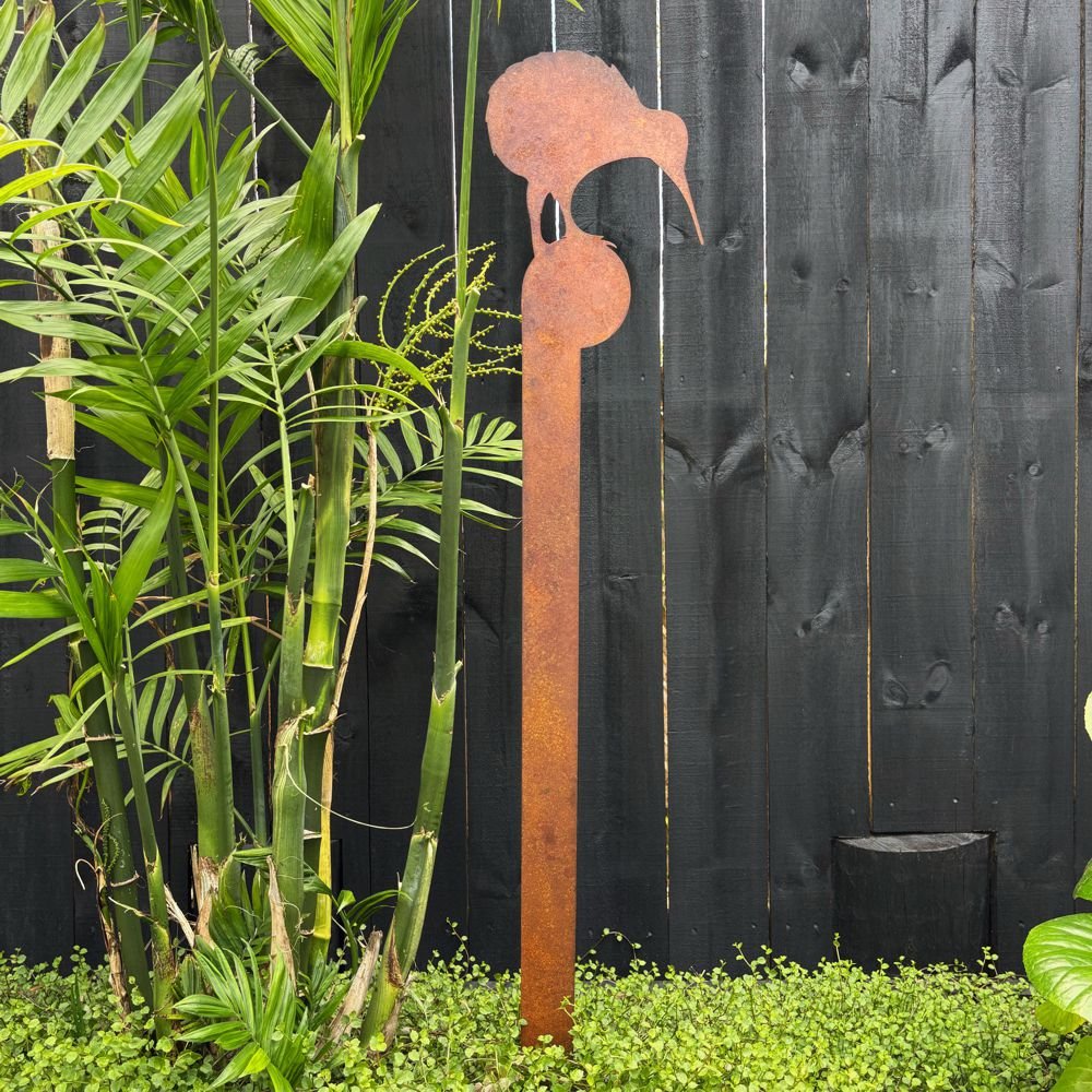 Close-up of rusted kiwi garden art stake with native NZ foliage behind. 