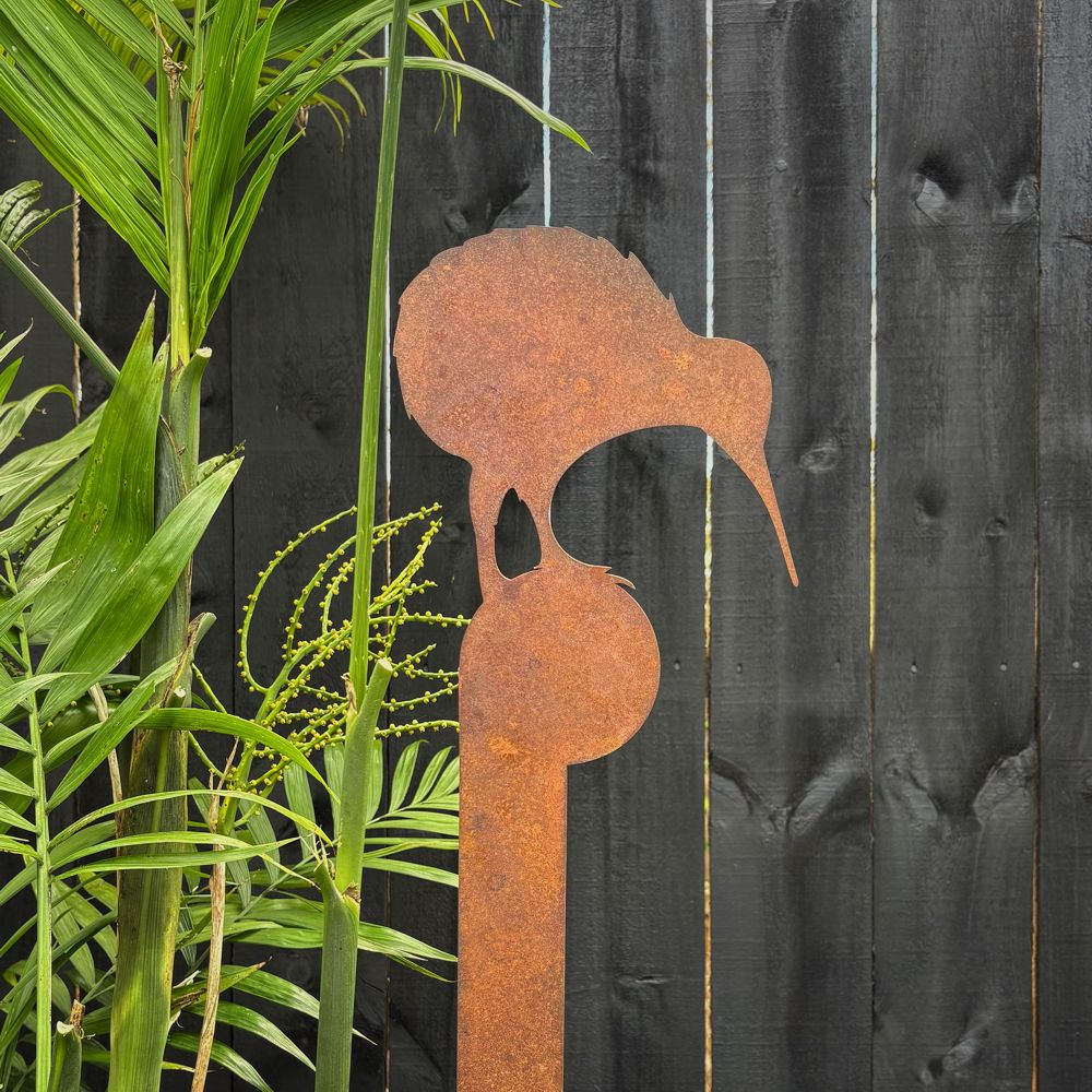 Close-up of rusted kiwi garden art stake with native NZ foliage behind. 