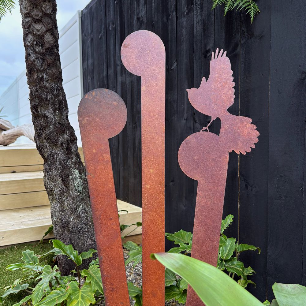 Set of 3 corten steel koru and fantail garden stakes in a New Zealand garden