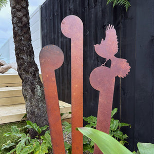 Corten steel koru and fantail garden art surrounded by NZ plants in a modern garden