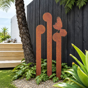 Set of 3 corten steel koru and fantail garden stakes in a New Zealand garden
