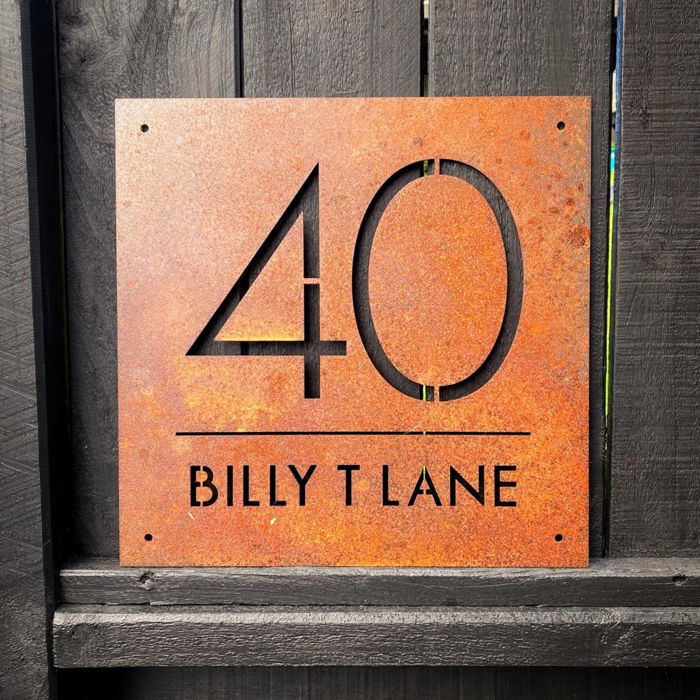 Front-on view of large square house number sign in matte black powdercoated steel mounted on exterior wall