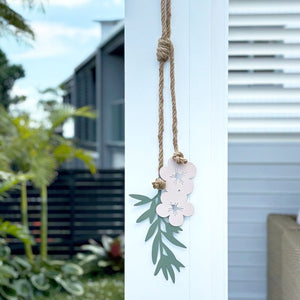 Decorative manuka flower wall hanging with pink flowers and green leaves in a modern outdoor space in Auckland, New Zealand. 