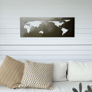 World map wall art in pewter bronze displayed above sofa in modern NZ home outdoor space