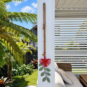 Decorative pohutukawa red and green outdoor wall hanging on post in Auckland garden 