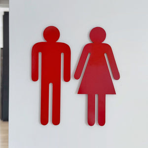 Close-up of red stainless steel bathroom symbols showing matte finish and precision-cut detail, made in New Zealand
