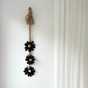 Decorative hanging with black floral shapes and jute rope on a white wall in living room in Australia.