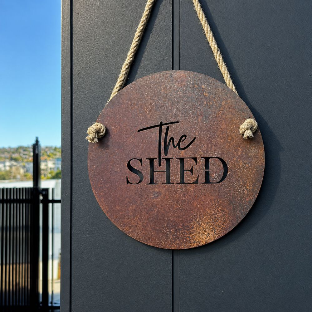 Round corten steel "the shed" sign mounted on a wall, NZ made