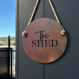 Round corten steel "the shed" sign mounted on a wall, NZ made
