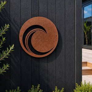 Round 50cm corten steel wave wall art mounted on a black fence in a New Zealand garden.