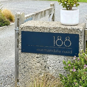 Custom address sign on stone wall on traditional rural fam in South Island, New Zealand.