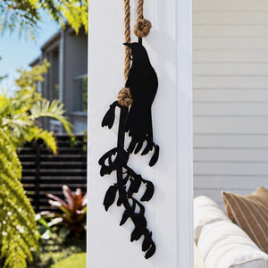 Close up black metal tui and harakeke wall hanging in patio