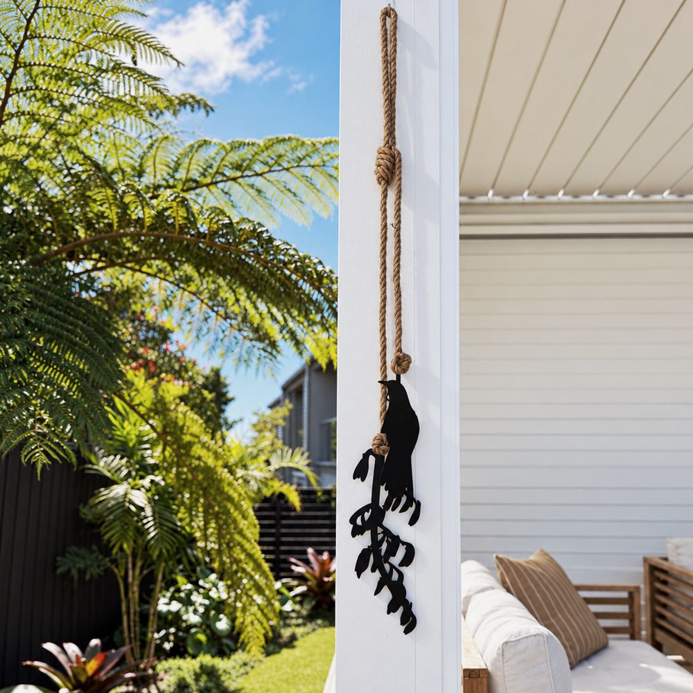 Black steel tui and harakeke flax wall hanging with natural rope, 1.2m long, hung on an outdoor patio wall