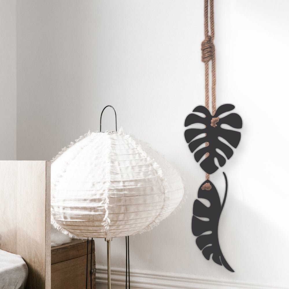 NZ-made black steel monstera leaf wall art hanging on patio wall